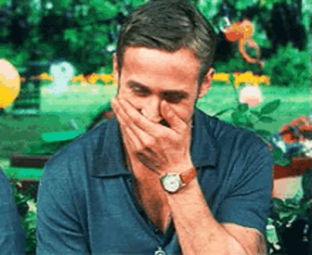 Ryan Gosling covering his mouth with his hands trying to control his laugh