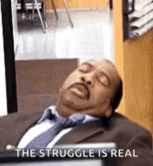 Man sleeping on a chair in the office with text saying 'the struggle is real'