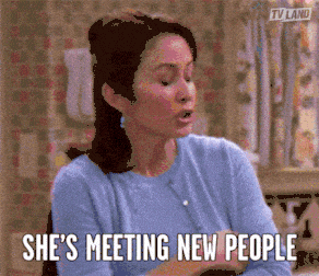 Woman in a kitchen with text 'SHE'S MEETING NEW PEOPLE'