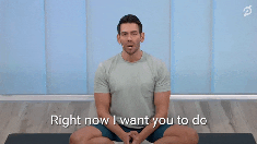 A man sitting in a cross-legged position, talking to the camera