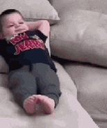 A baby lying on its back on a couch.