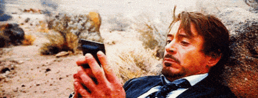 Robert Downey Jr. lying on a rock reading something very long on his phone