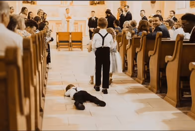 Two small kids in a church and one is lying on the ground
