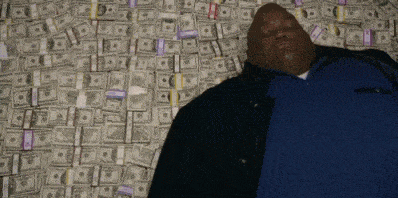 Huell from Breaking Bad lying down on a large pile of money.