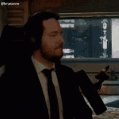 A man in a suit gesturing with a microphone.