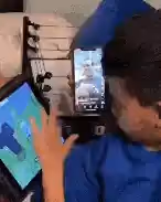 A person holding a phone vertically displaying a video while another person's hand interacts with a tablet showing a map-like interface.