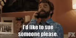 A man with a beard talking on a phone with a serious expression and the caption "I'd like to sue someone please."