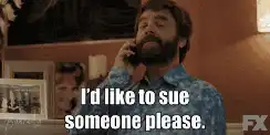 A man with a beard talking on a phone with a serious expression and the caption "I'd like to sue someone please."