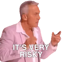 A man in a pink jacket and white shirt gestures with his hands, with white text overlayed that reads 'IT'S VERY RISKY'.