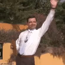 Mr. Bean waving enthusiastically with his right arm raised high.