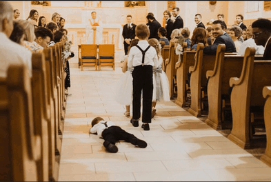 Two small kids in a church and one is lying on the ground