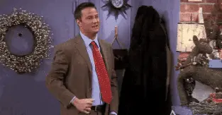 Chandler Bing from Friends in a suit and red tie.