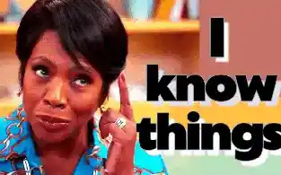 A Black woman with dark curly hair wearing a blue shirt with a gold chain print looks thoughtful and says "I know things"