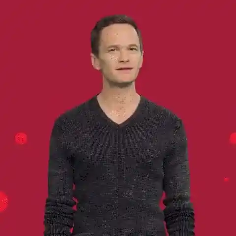 Neil Patrick Harris stands against a red background with small red circles.