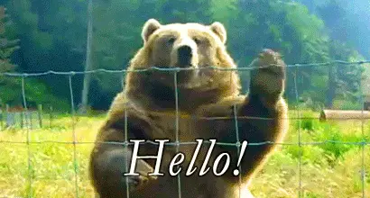 A bear waves hello through a fence.