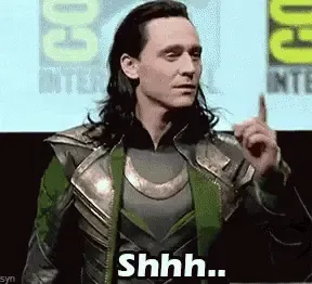 Loki holds a finger to his lips in a