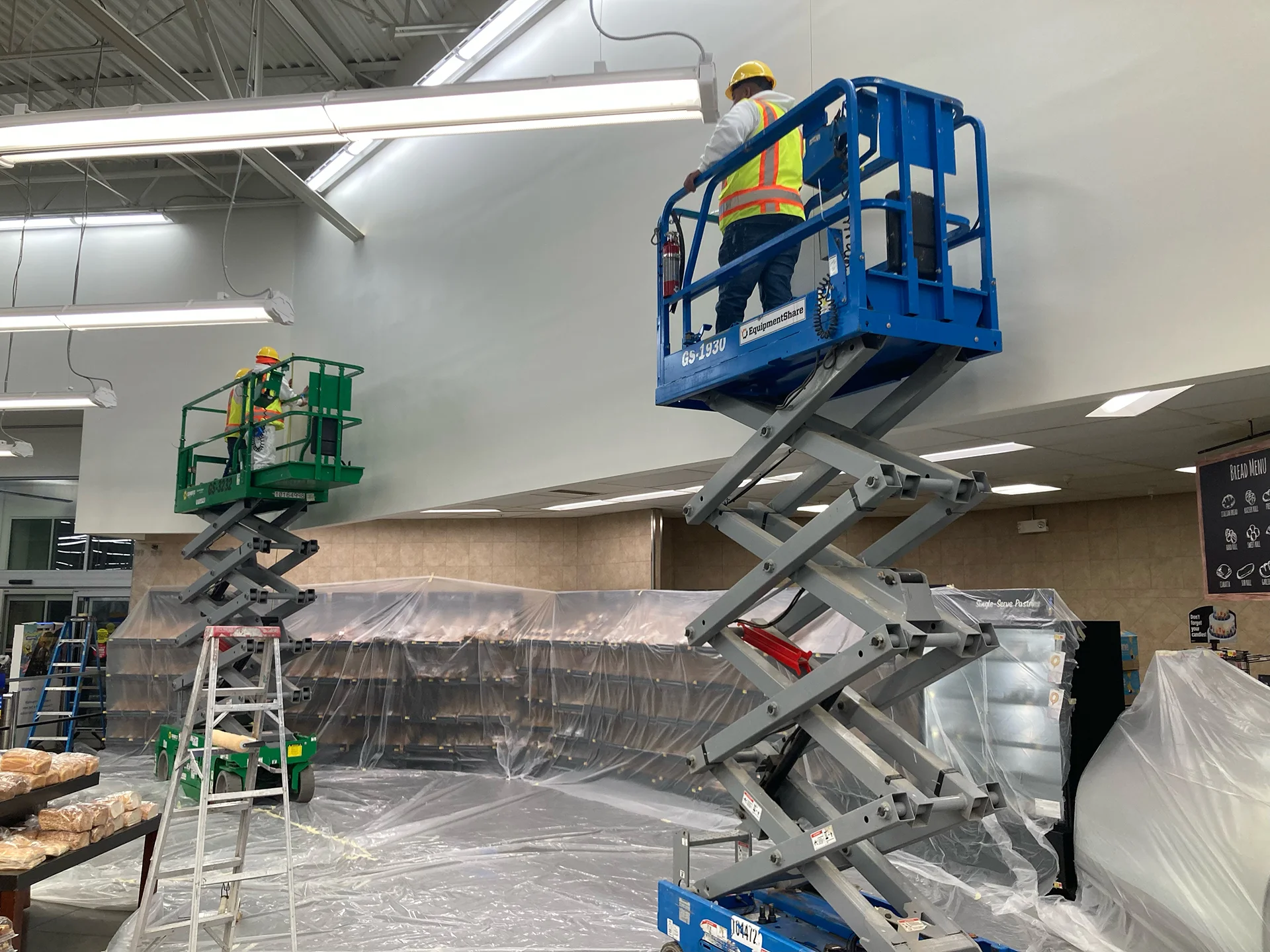painter on a lift to paint very high ceilings in a commercial warehouse