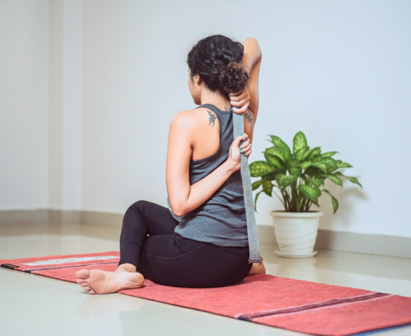 Woman practicing a seated side stretch while following an online yoga class on a tablet.