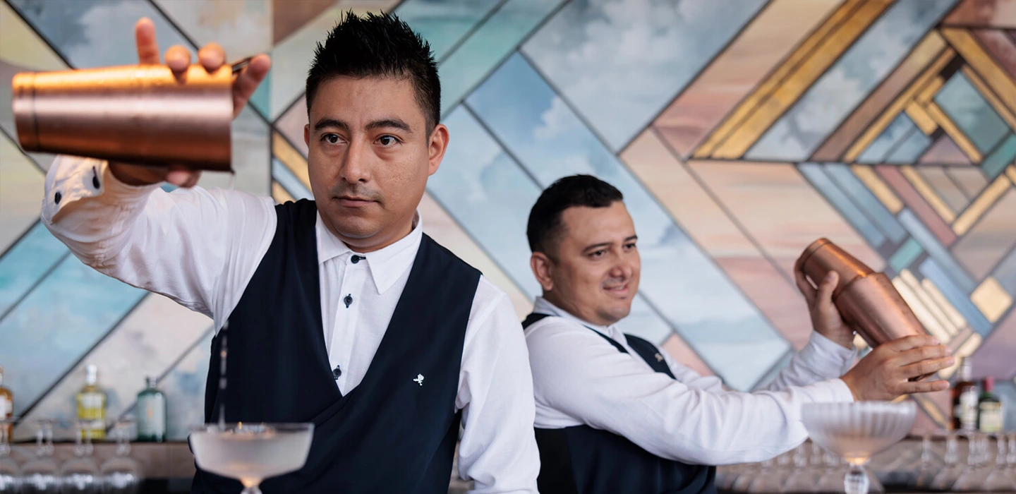 Two male Marriott bartenders thoughtfully mixing cocktails. 