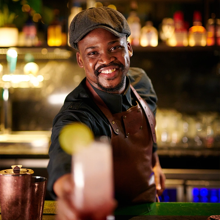 Male bartender serving a drink and smiling.