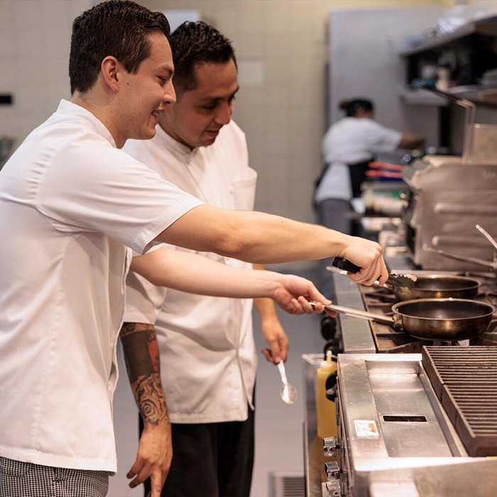 Two male chefs preparing food in a professional kitchen.