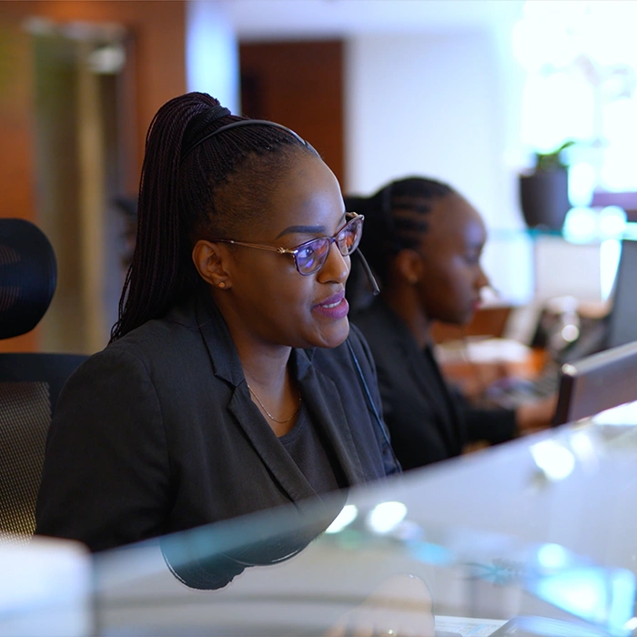 Female receptionist smiling whilst sitting behind desk.