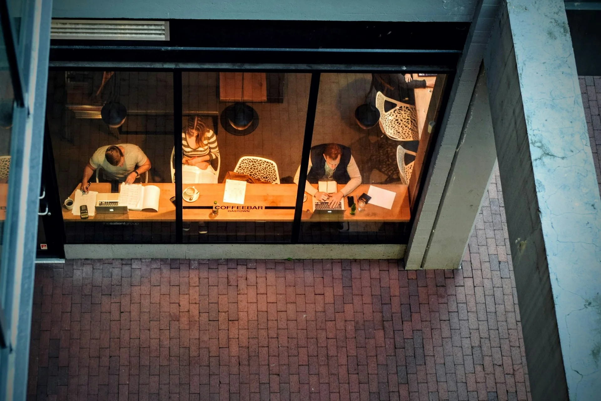 A photo looking down on a coffee shop window where people working can be seen.