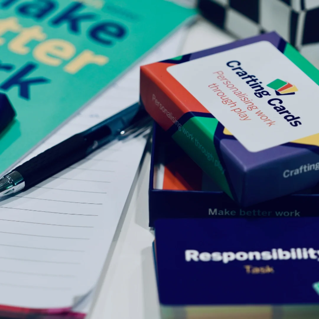 A photo of Tailored Thinking's "Crafting Cards", a scalable tool for implementing ob crafting in the workplace. Next to the Cards is Tailored Thinking's brochure, which reads "Make Work Better, Make Better Work".