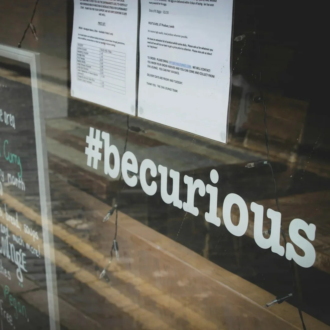 A photograph of a window display that says "#becurious" under the menu.