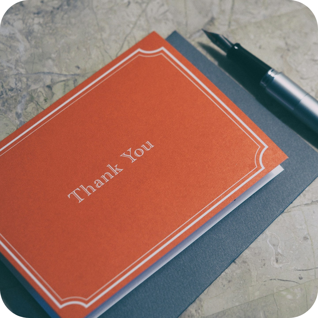 A brightly coloured thank you card with a very nice fountain pen laying next to it.