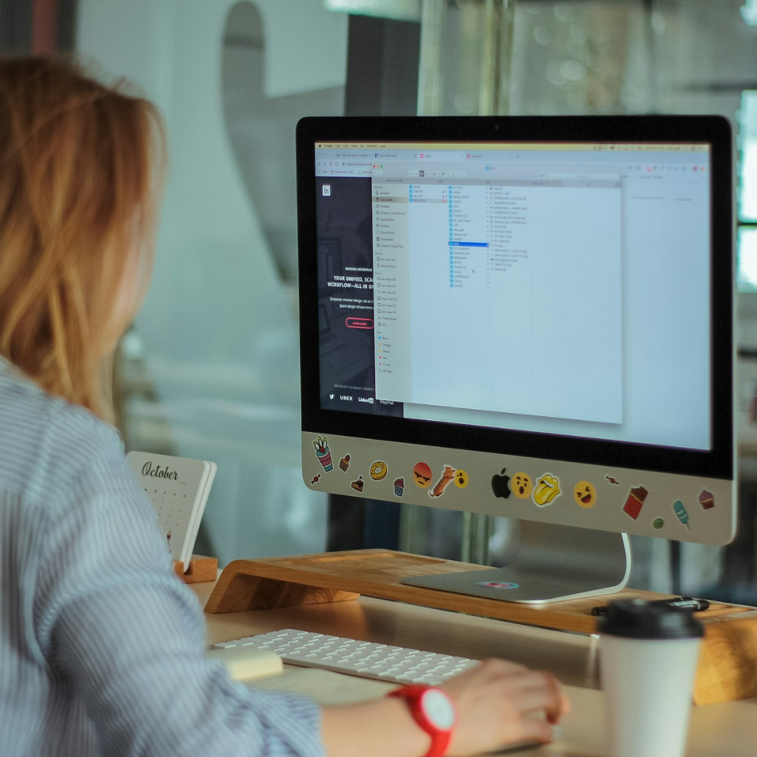 A female employee sat at her computer, which is personalised with loads of different stickers.