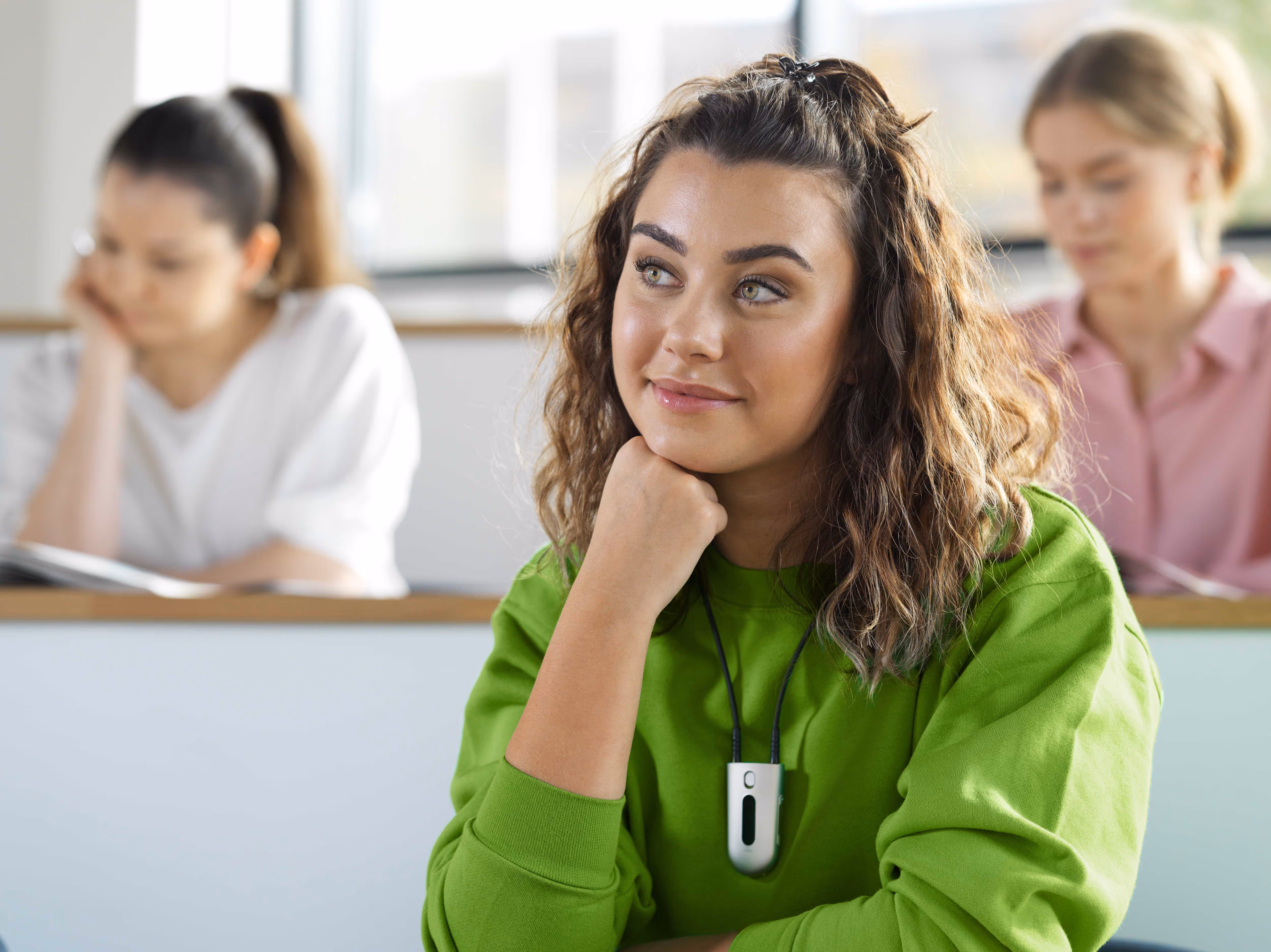 A woman in a green sweater attentively listens during a class.