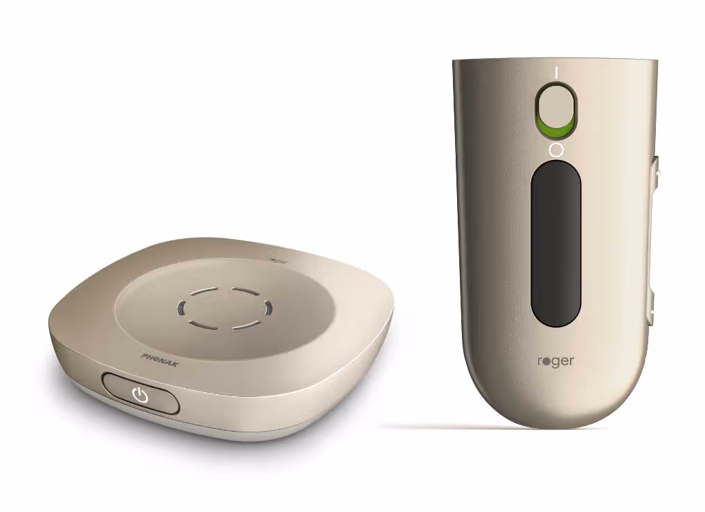 Two beige electronic hearing devices, one round with a power button, the other handheld with display.