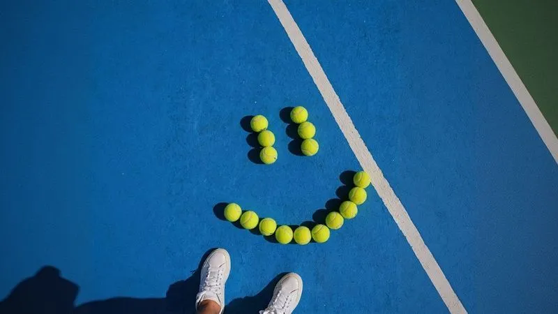 A tennis court with a smiley face made out of tennis balls.
