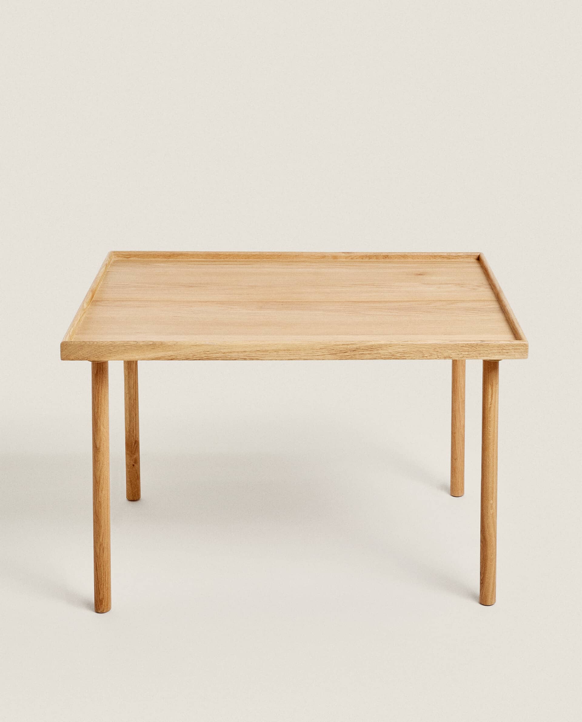 Front view of a square Oat table in light oak, with a raised rim and four slim round legs.