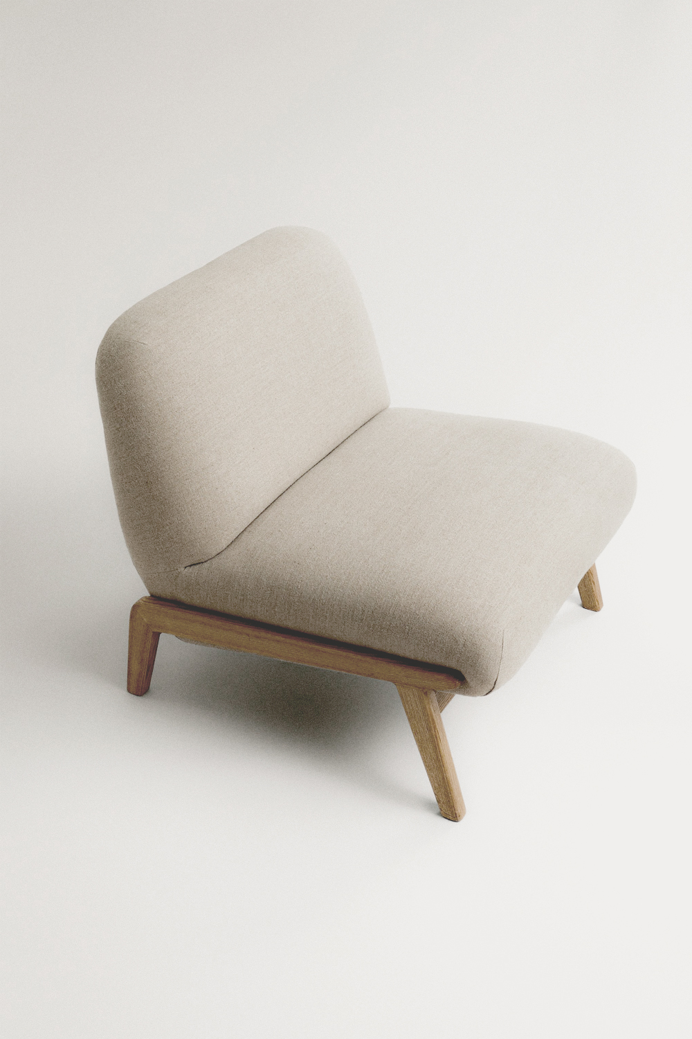 Beige Camilla chair seen from above, with a soft rounded back and seat on slim light oak legs, against a pale background.