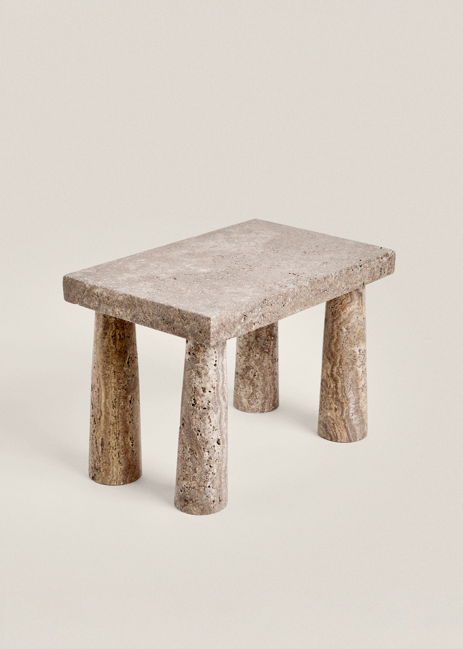Three-quarter view of the Tap stool in brown travertine, with a smooth rectangular top and four rounded legs.