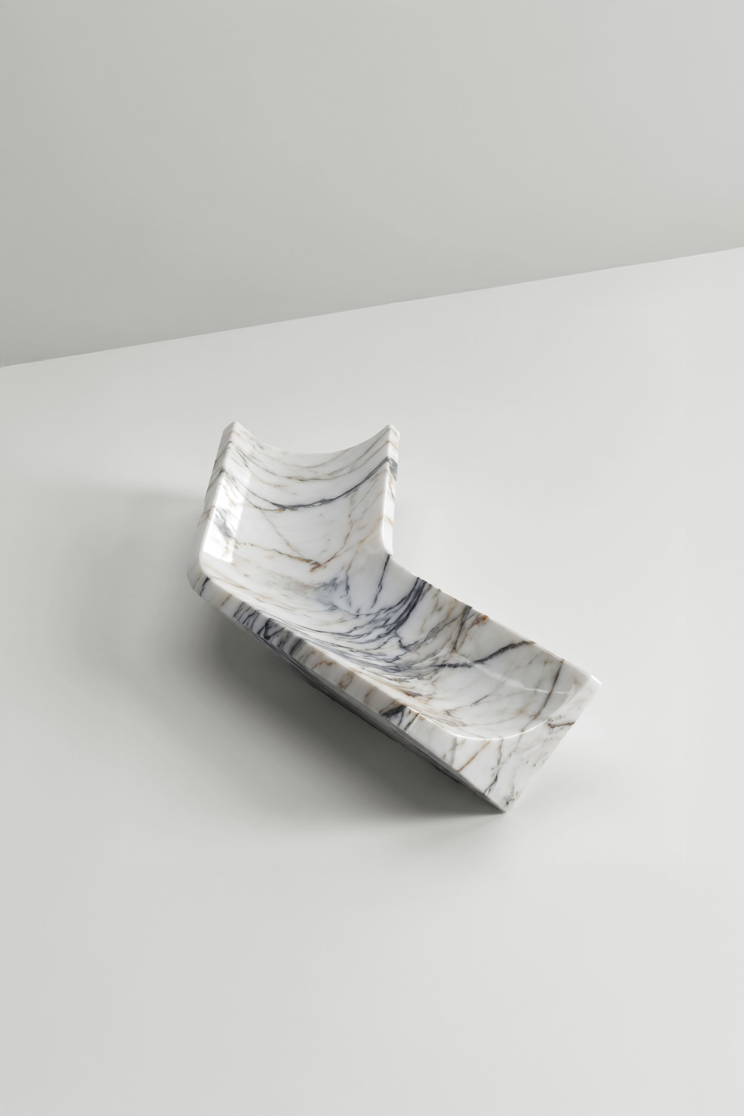 White marble Bow tray with grey veining, an L-shaped tray with a curved dip, seen from above on a pale surface.