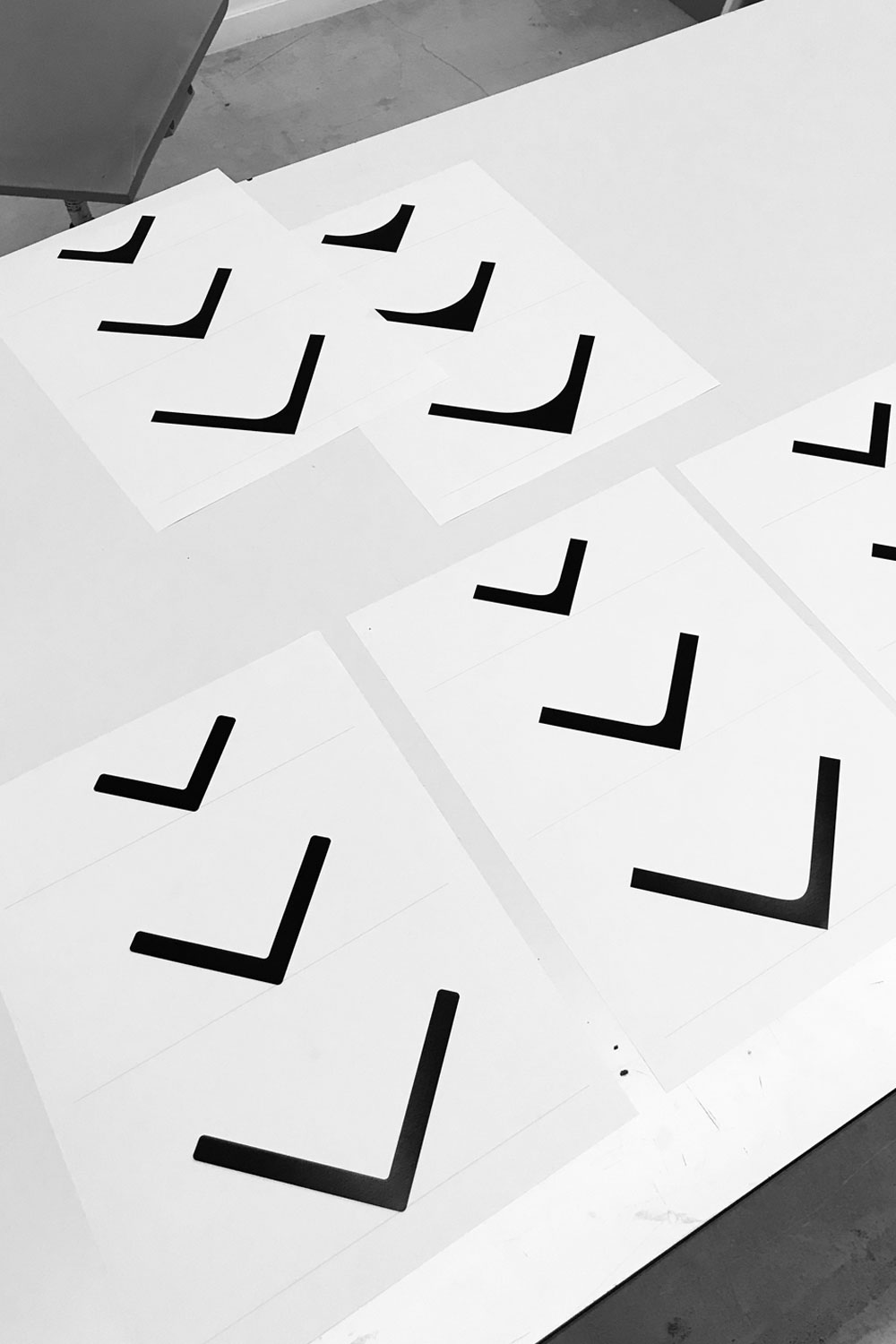 Black and white photo of printed sheets with black bent L-shaped forms, the tray profile sketches.