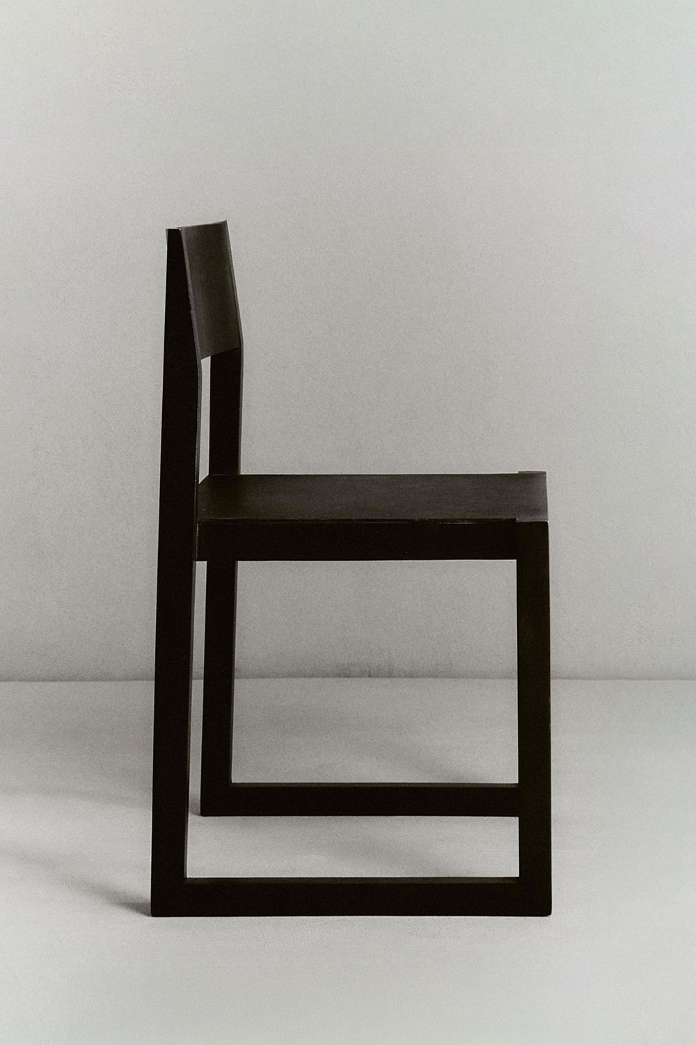 Ray chair in profile, with a dark sled base and angled backrest