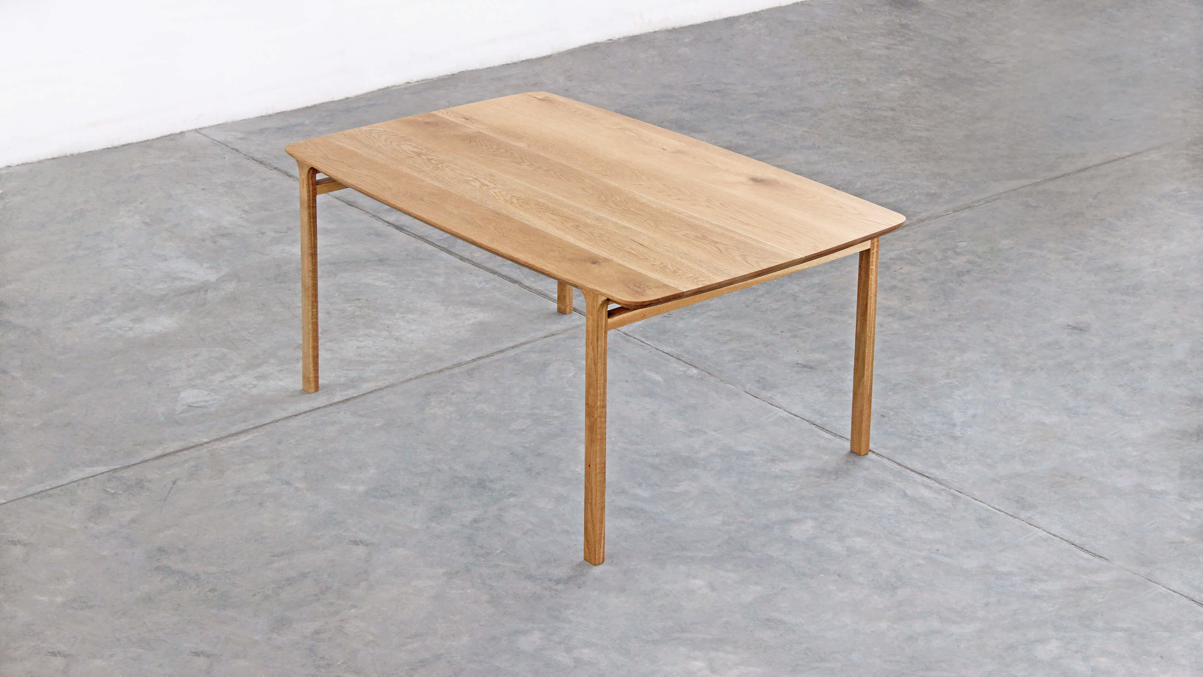 Three-quarter view of the Feynman table from above, on a concrete floor in the corner of a white room.