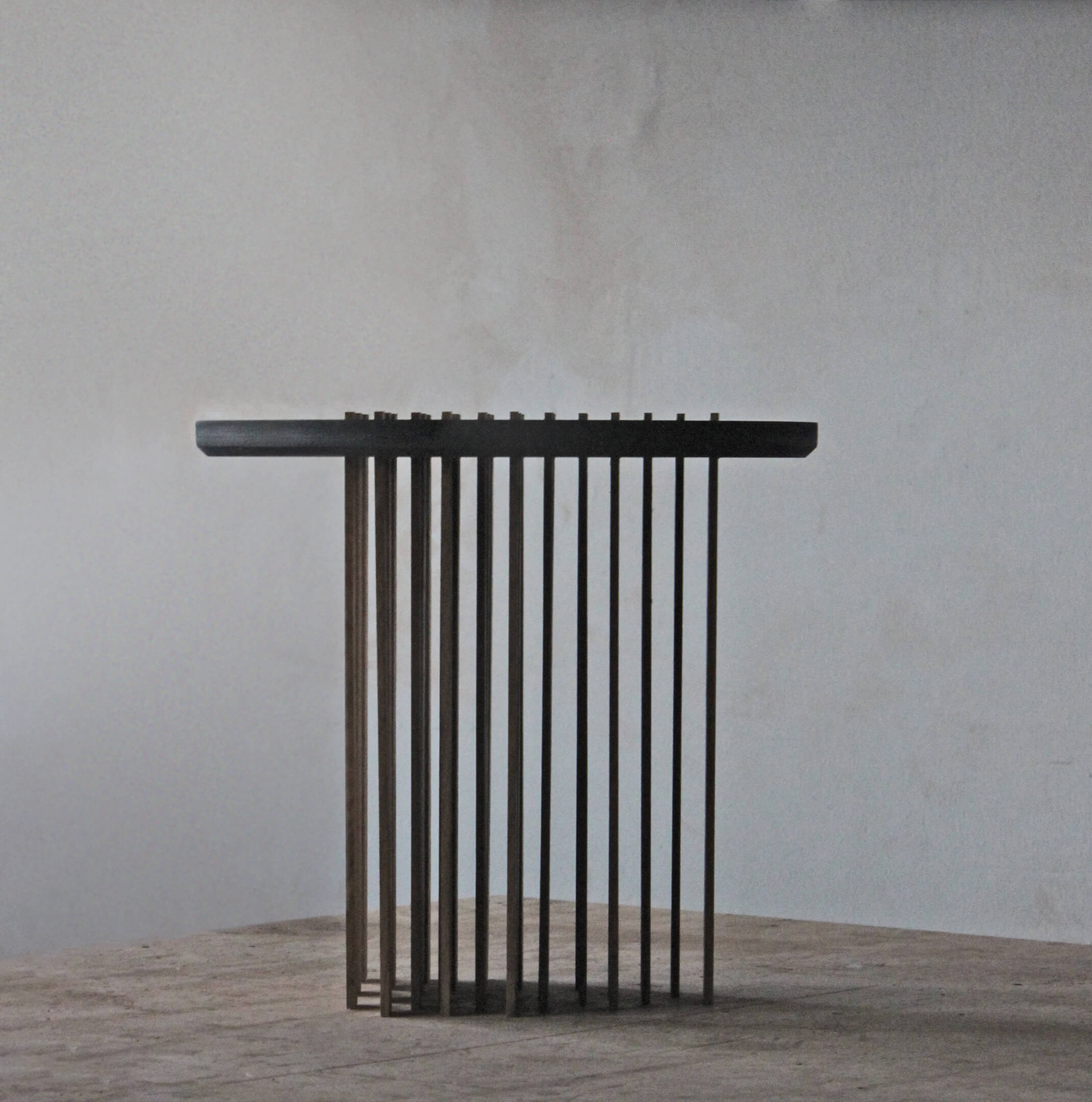 Close-up of the table's oak slat legs standing in rows, with the grain visible and the grey wall behind.