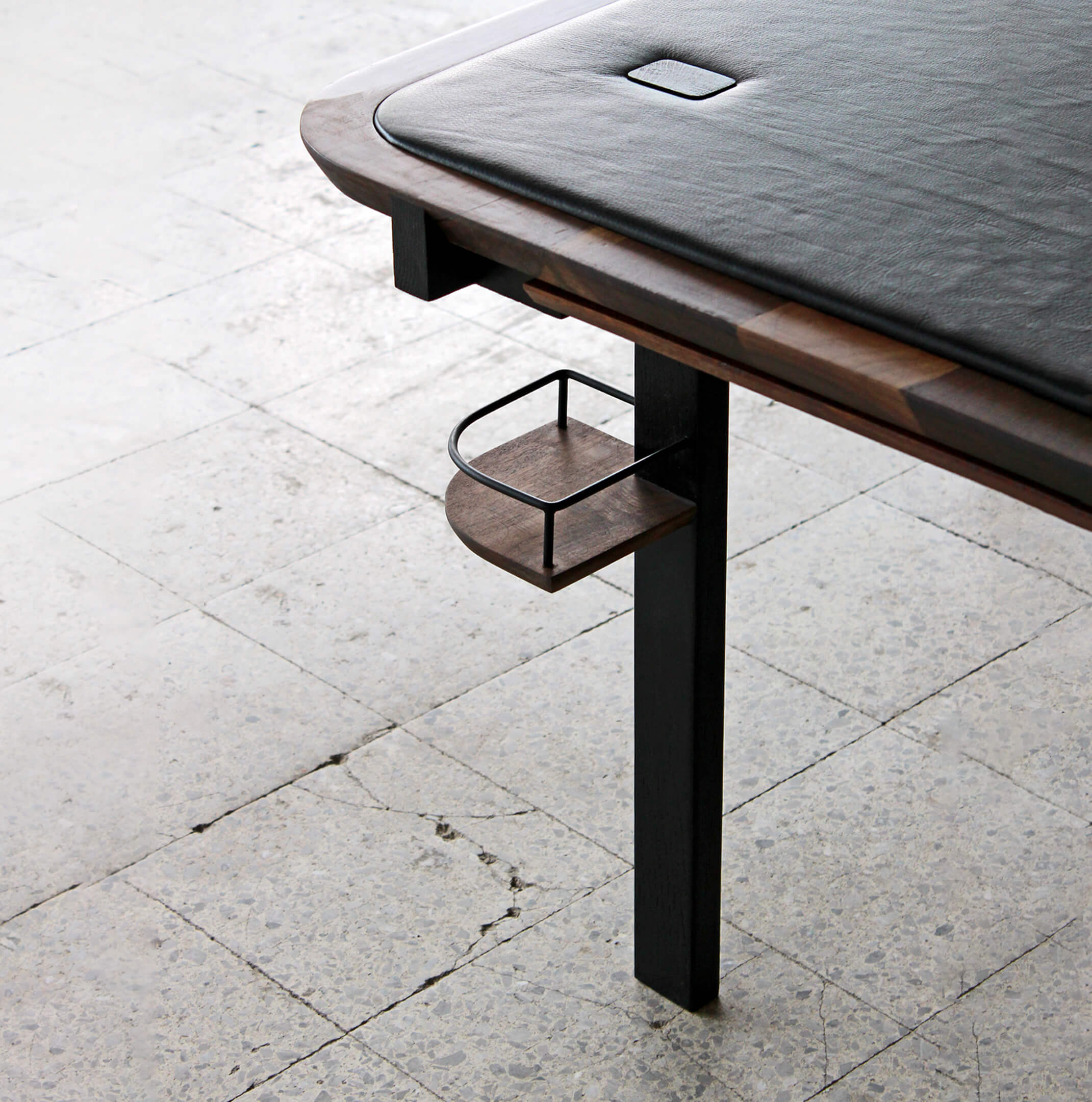 A detail of the Planck Table in walnut wood and black leather