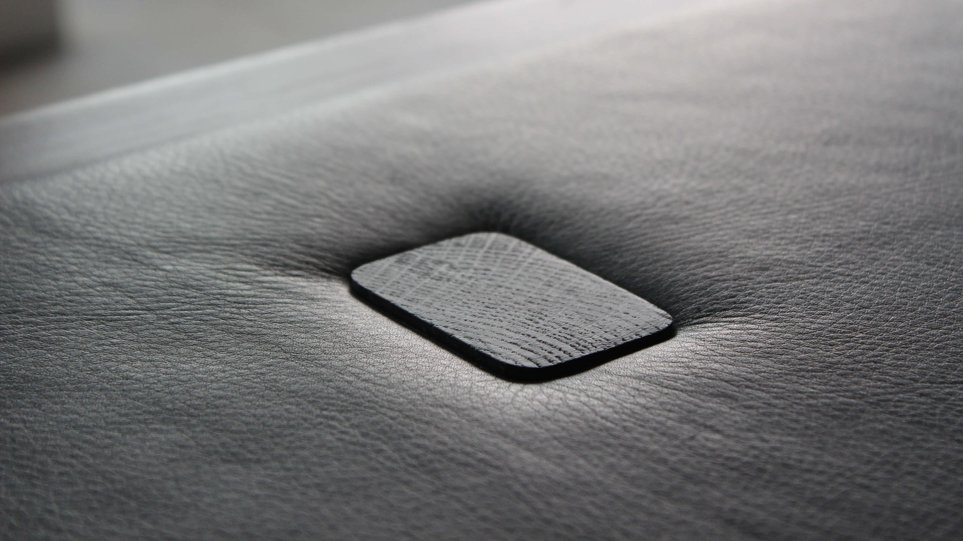 Macro of the leather top's small black wooden button, with the leather gathered softly around it.