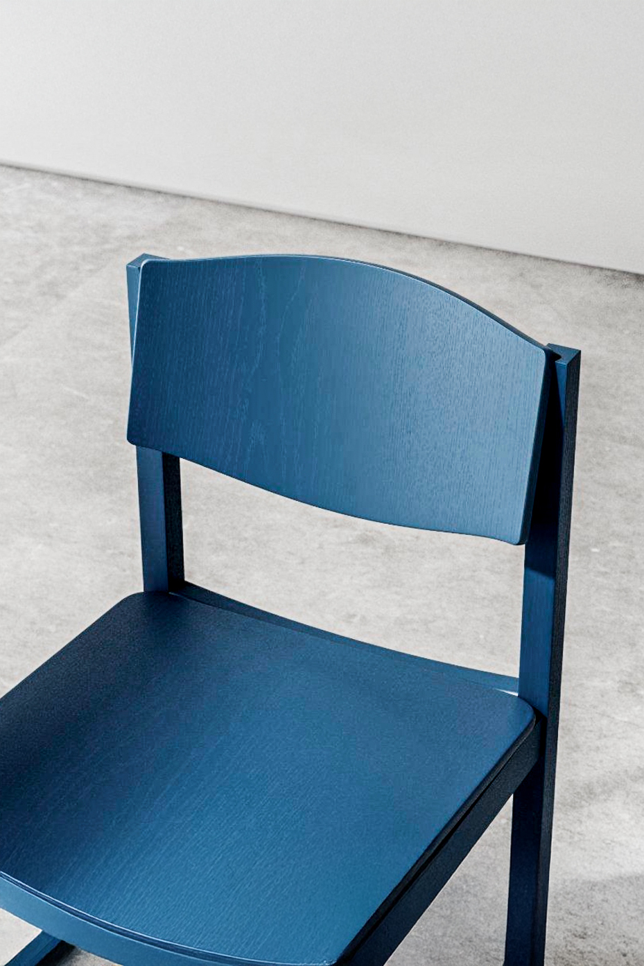 Close-up of the blue backrest, a wavy-topped panel with visible wood grain, set between two square uprights above the seat.