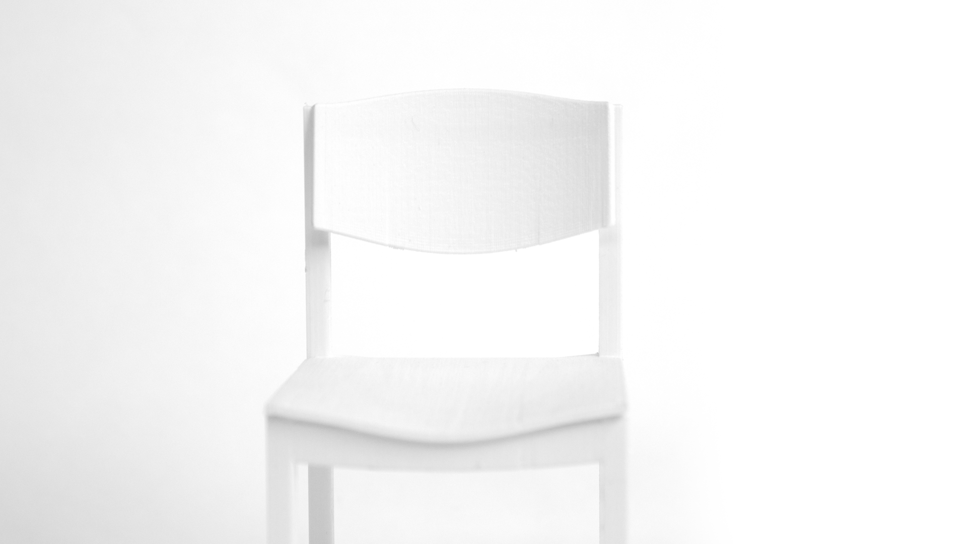 Side detail of the blue chair, with the curved backrest panel, the dished seat and the square frame, in soft daylight.