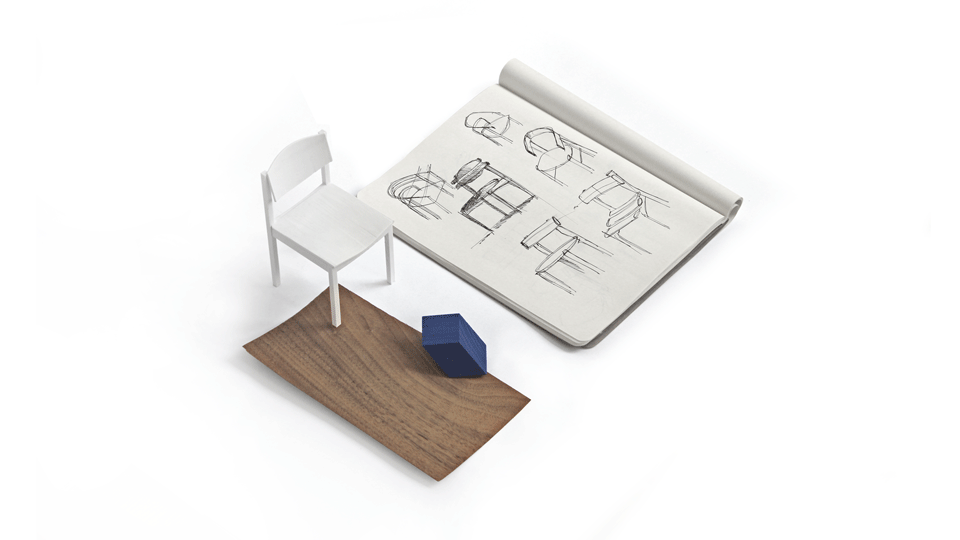 Side detail of the blue chair, with the curved backrest panel, the dished seat and the square frame, in soft daylight.