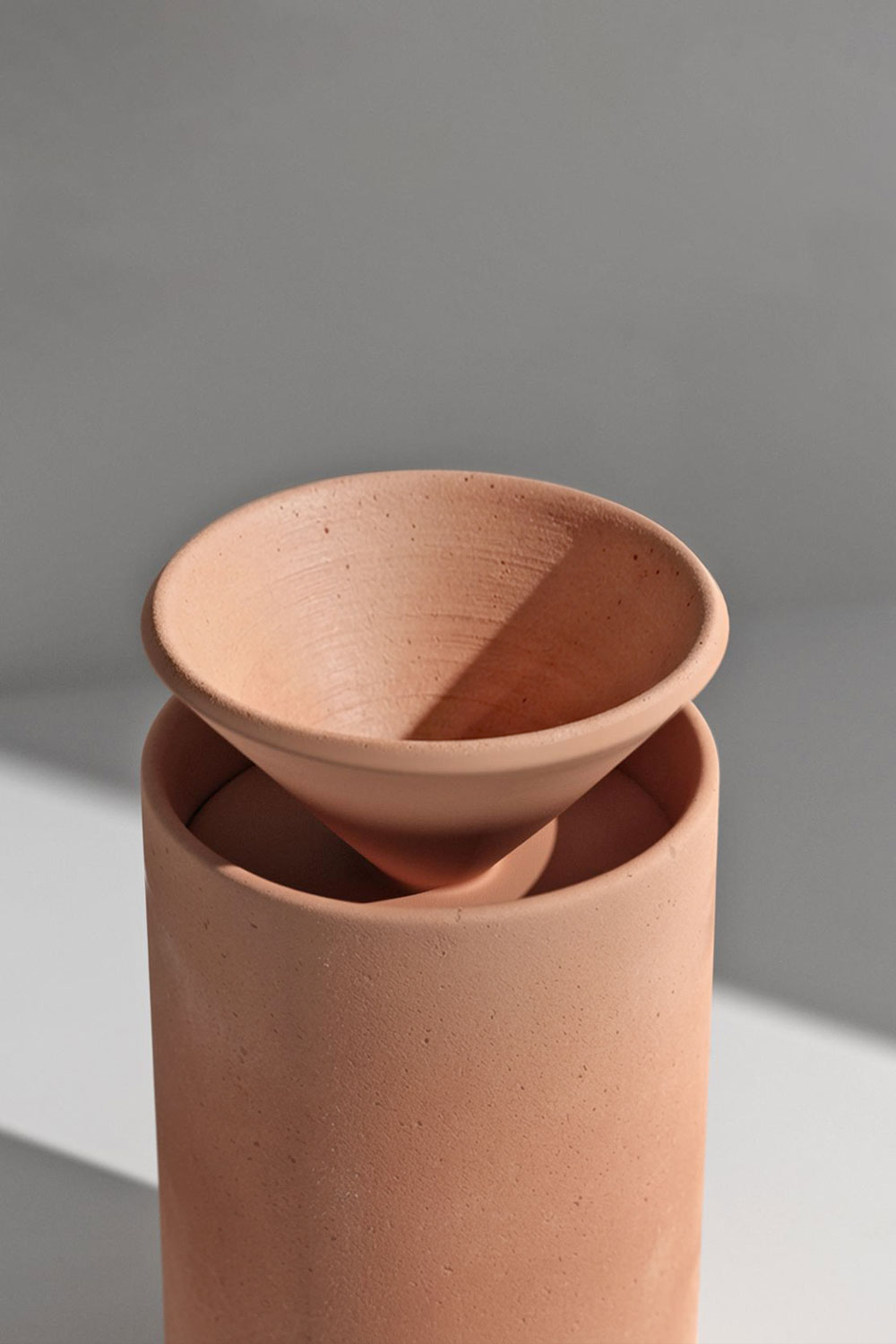 Olla coffee dripper in dark terracotta: a tall speckled cylinder with a shallow conical filter holder resting on top.