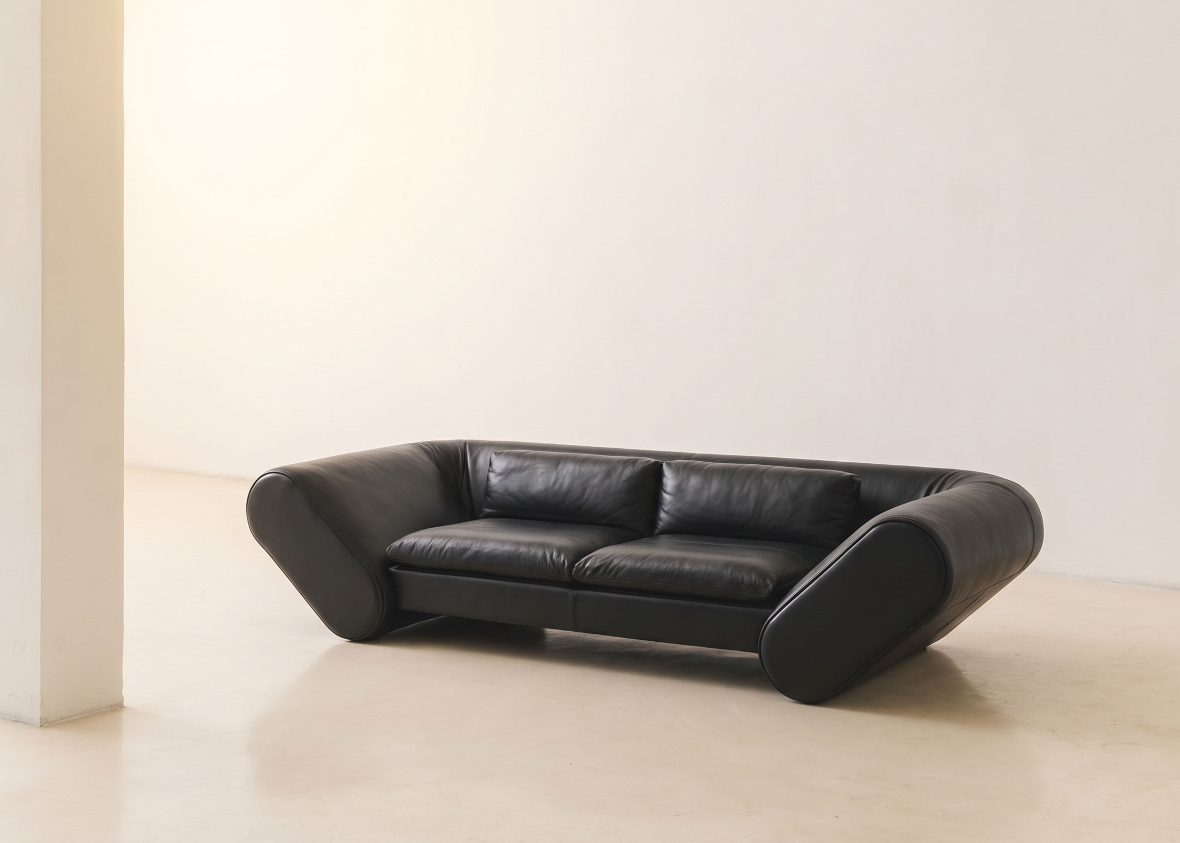 Front view of the black leather Lee sofa, with two seat and back cushions between two tilted, rounded arms.