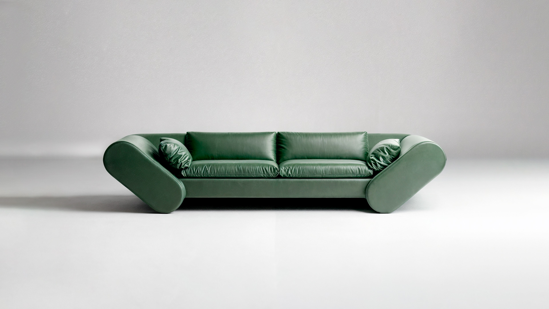 Lee sofa in green leather with two small scatter cushions, centered against a pale grey background.